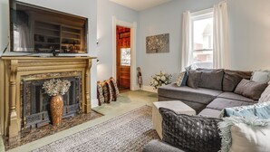 A living room with a fireplace, a sofa, and a television. - Walkable Group Getaway w/ Bikes in West Liberty! (West Liberty)