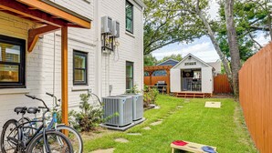 Il s’agit d’une propriété résidentielle à l’extérieur blanc, dotée d’une terrasse en bois et d’une cour arrière avec pelouse et arbres.