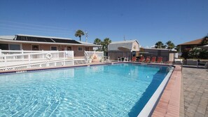 A swimming pool with a white deck, lounge chairs, and a building in the background. - 2BR Direct Ocean Complex • Beach Access • Pool • Free Parking (Cocoa Beach)