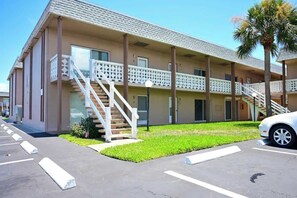 A two-story motel with a central staircase, a parking lot, and a palm tree.