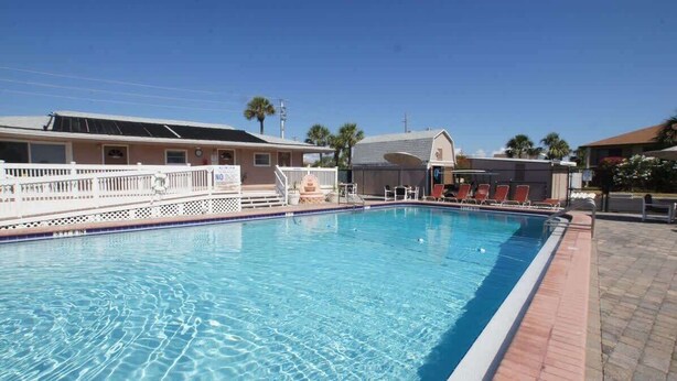 A swimming pool with lounge chairs and a small building in the background. - Direct Ocean Complex! Diplomat 220-21 (Cocoa Beach)