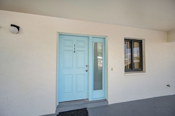 A light blue door with a glass panel, a small window with a curtain, and a wall-mounted light fixture.