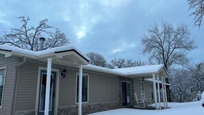 Une maison à deux étages, dotée d’un porche abrité et d’un toit recouvert de neige.