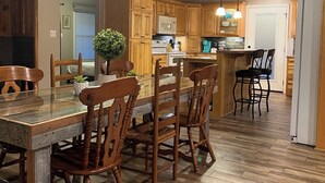 Une cuisine aux murs lambrés, avec un coin repas, dotée d’un ventilateur de plafond, de luminaires suspendus et d’un plancher en bois.