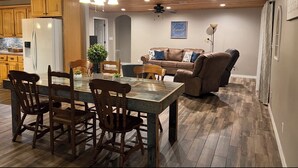 Un vaste espace de vie comprenant une table à manger, des chaises, un canapé et un ventilateur de plafond.