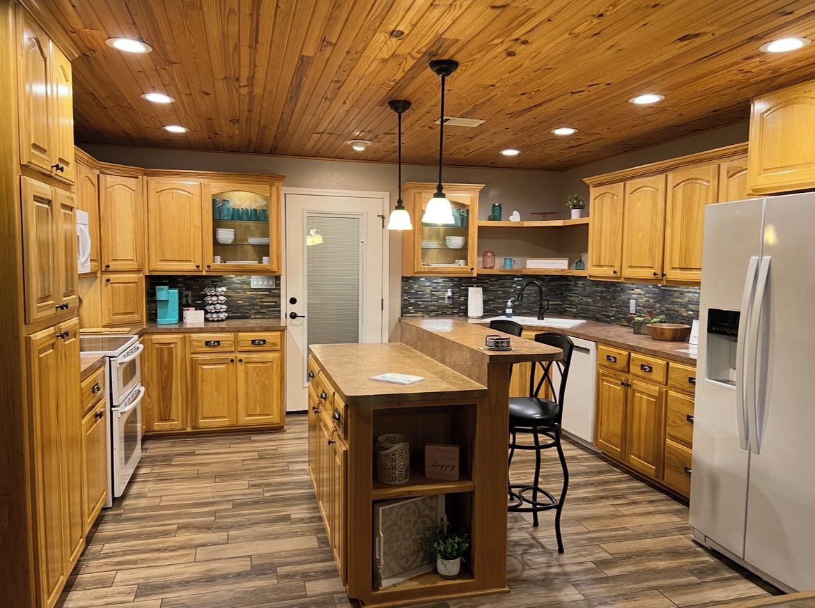 A kitchen with wooden cabinets, a central island, and a refrigerator.