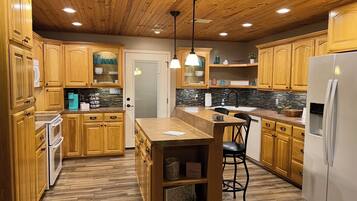 A kitchen with wooden cabinets, a central island, and a refrigerator.