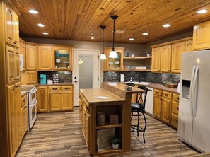 Une cuisine avec des meubles en bois, un îlot central et un réfrigérateur.