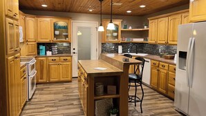 Une cuisine avec des meubles en bois, un îlot central et un réfrigérateur.
