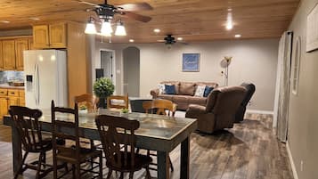 A spacious living area with a dining table, chairs, a sofa, and a ceiling fan.