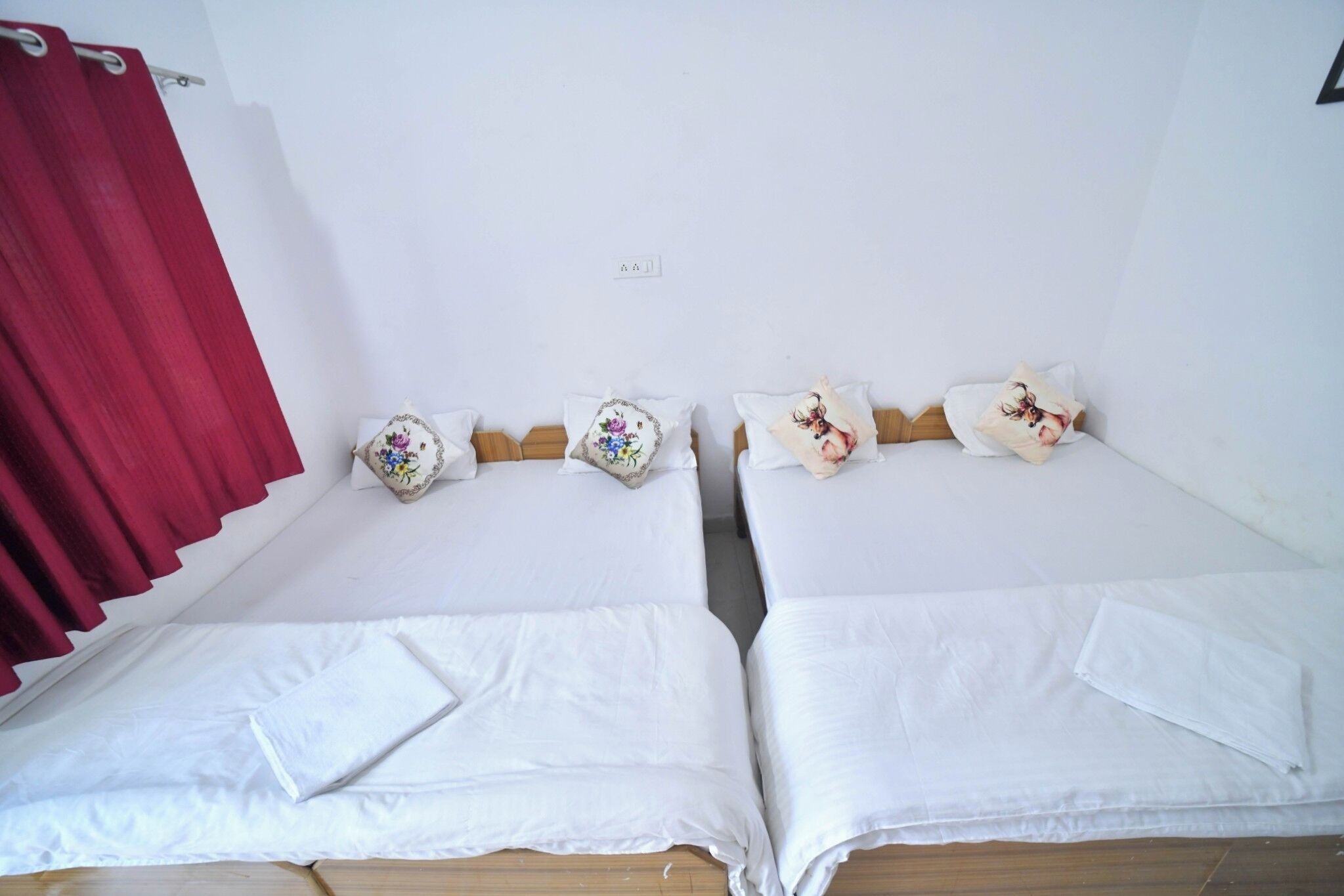 A room with two single beds, each with a pillow and a small decorative pillow.