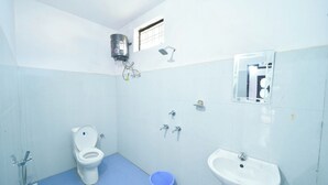 Une petite salle de bain propre, équipée de toilettes, d’un lavabo et d’une douche.