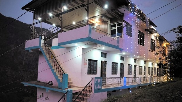 Un immeuble à plusieurs étages, doté d’un escalier menant aux étages supérieurs, d’un balcon supérieur couvert et de guirlandes lumineuses le long de la façade.