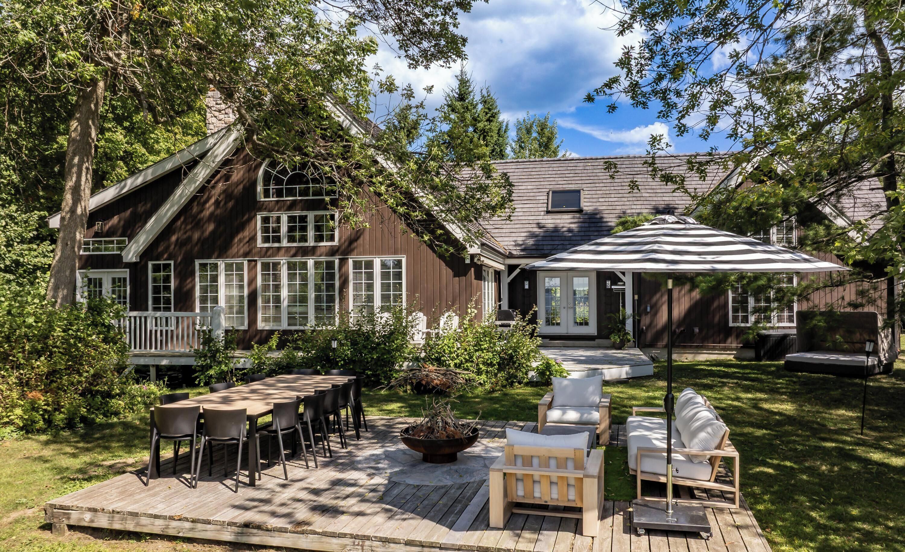 A wooden deck with outdoor furniture, a barbecue grill, and a covered patio area.