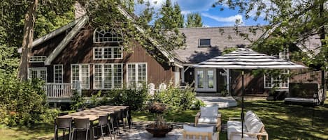 A wooden deck with outdoor furniture, a barbecue grill, and a covered patio area.