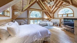 Une chambre spacieuse de style loft, dotée d’un grand lit, d’une télévision et d’un coin salon confortable.