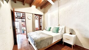 Ein Schlafzimmer mit einem hölzernen Bett, einem weißen Nachttisch und einem Deckenventilator.