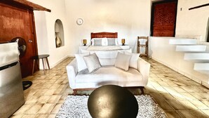 A modern living room with a white sofa, a round black coffee table, and a wooden-framed ceiling.