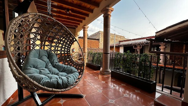 A hanging chair on a tiled patio with a view of a cityscape.