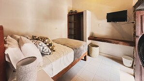 A bedroom with a bed, pillows, a wooden headboard, a television mounted on the wall, and a small shelf. - Hotel Room, one block from the Lake centr 3 (Valle de Bravo)