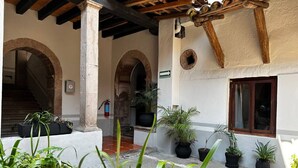 A courtyard with potted plants, a fire extinguisher, and a staircase leading to an upper level. - Hotel Room, one block from the Lake centr 3 (Valle de Bravo)