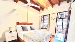Une chambre à coucher avec un lit en bois, une table de chevet blanche et un ventilateur de plafond.