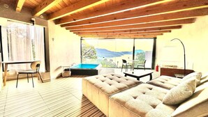 Un salon moderne avec un plafond en bois, un grand canapé confortable, une petite table et une vue sur l’extérieur.