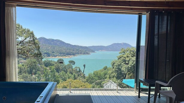 Un balcon avec vue sur un lac et des montagnes, une table de billard et un fauteuil.