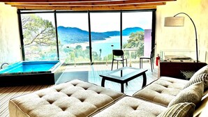 Un salon moderne avec une piscine, de grandes fenêtres et une vue sur la mer.
