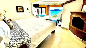 A bedroom with a large bed, a fireplace, and a view of the sea. - Jacuzzi Apartment Lake View, Heated Pool 7 (Valle de Bravo)