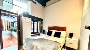 A bedroom with a bed, two bedside tables, a nightstand, a clock, and a window. - Hotel Room Type 2 (Valle de Bravo)