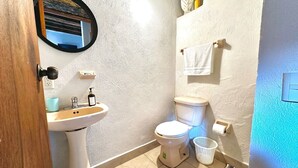 Et badeværelse med et håndvaskesæt, toilet og et håndklædestativ.