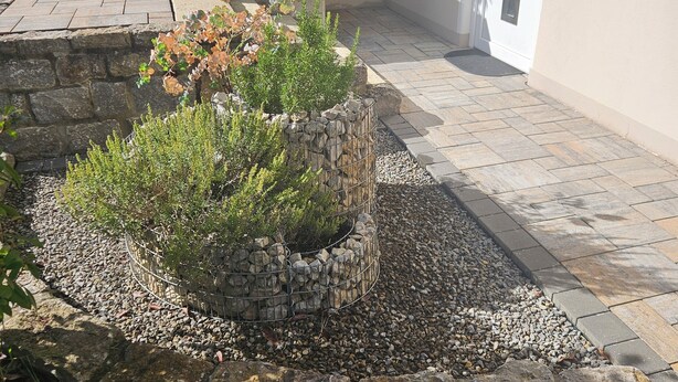 A stone staircase leading to a door, a small garden area with plants and gravel, and a tiled patio area. - Modern vacation apartment in a very beautiful location, surrounded by forests and hiking trails! (Heimbuchenthal)
