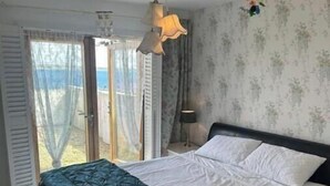 A bedroom with a bed, a bench, a lamp, and a view through a door. - Atlantic Views & Irish Charm (Ballycotton)
