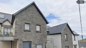 A residential building with a stone facade, a balcony, and a garage. - Atlantic Views & Irish Charm (Ballycotton)