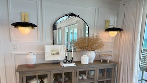 A wooden console with glass doors, a mirror, and two wall-mounted lamps.
