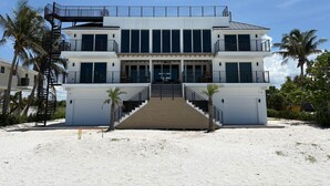 A two-story beachfront property with a central staircase, large windows, and a covered front porch.