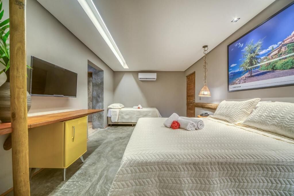 A modern hotel room with a bed, a television, a desk, and a large window.