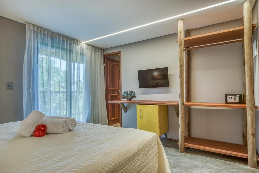 Une chambre d’hôtel équipée d’un lit, d’un bureau, d’une télévision et d’une armoire.