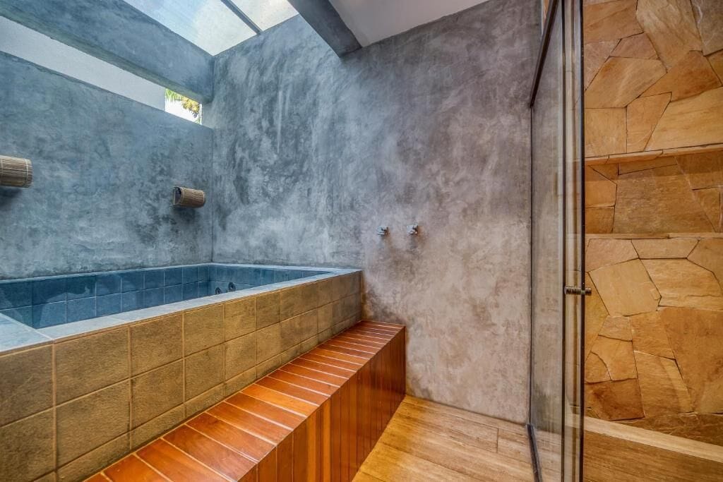 Een moderne badkamer met een groot bad, een douche en een dakraam.