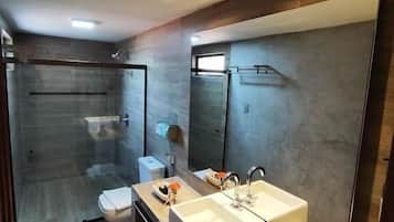 Uma casa de banho moderna com cabine de duche em vidro, lavatório duplo e um espelho grande.
