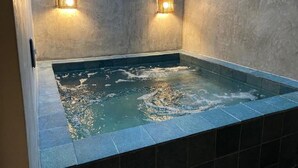 Un jacuzzi con dos luces empotradas, rodeado de piso y paredes con azulejos.
