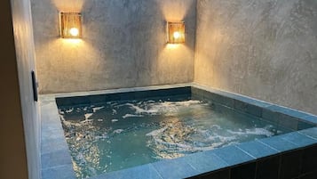 Un jacuzzi con dos luces empotradas, rodeado de piso y paredes con azulejos.