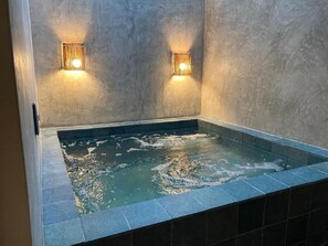 A hot tub with two wall-mounted lights, surrounded by a tiled floor and walls. - Villa Italiana (São Miguel dos Milagres)