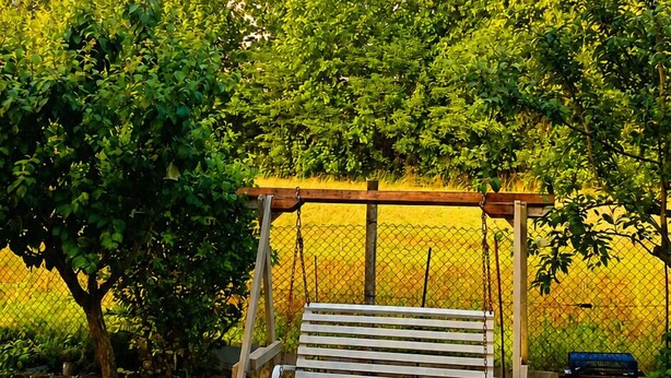A wooden swing set in a lush garden with a rainbow in the background. - Cristina's House (Martellago)