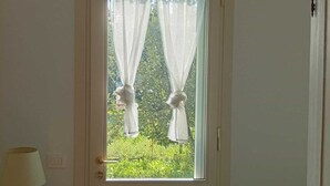 A white door with a window, a lamp on a side table, and a bed with a striped bedspread. - Cristina's House (Martellago)