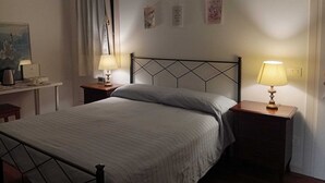 A bedroom with a bed, two bedside tables with lamps, a window with curtains, and a painting on the wall. - Cristina's House (Martellago)