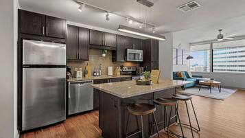 A modern kitchen with dark cabinets, stainless appliances, and a central island with stools.