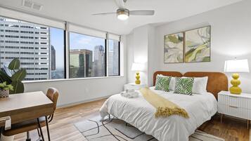 A modern hotel room with a large bed, two bedside tables, a desk, and a chair.