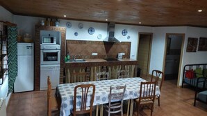 A compact kitchen with a dining area, wooden ceiling, and tiled backsplash.